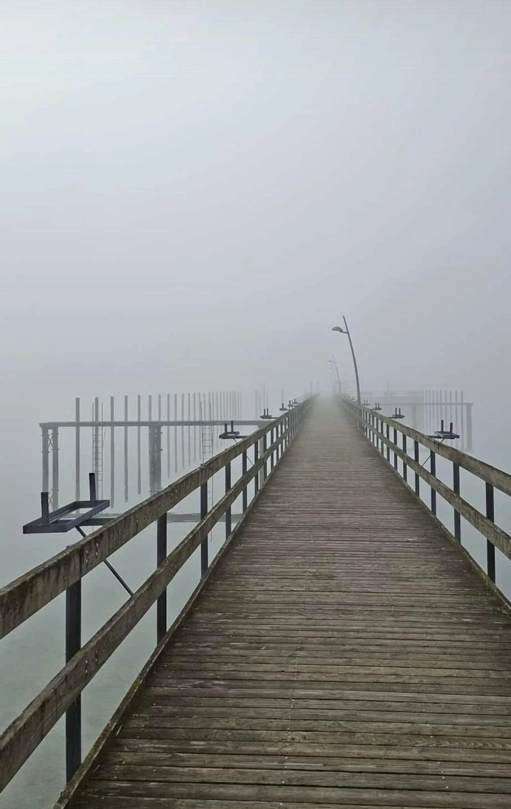 Ein langer Holzsteg führt über das stille Wasser.